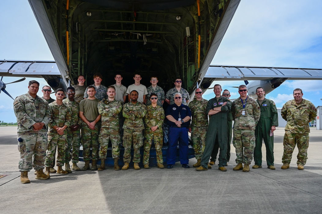 A group of people pose in front of an airplane.