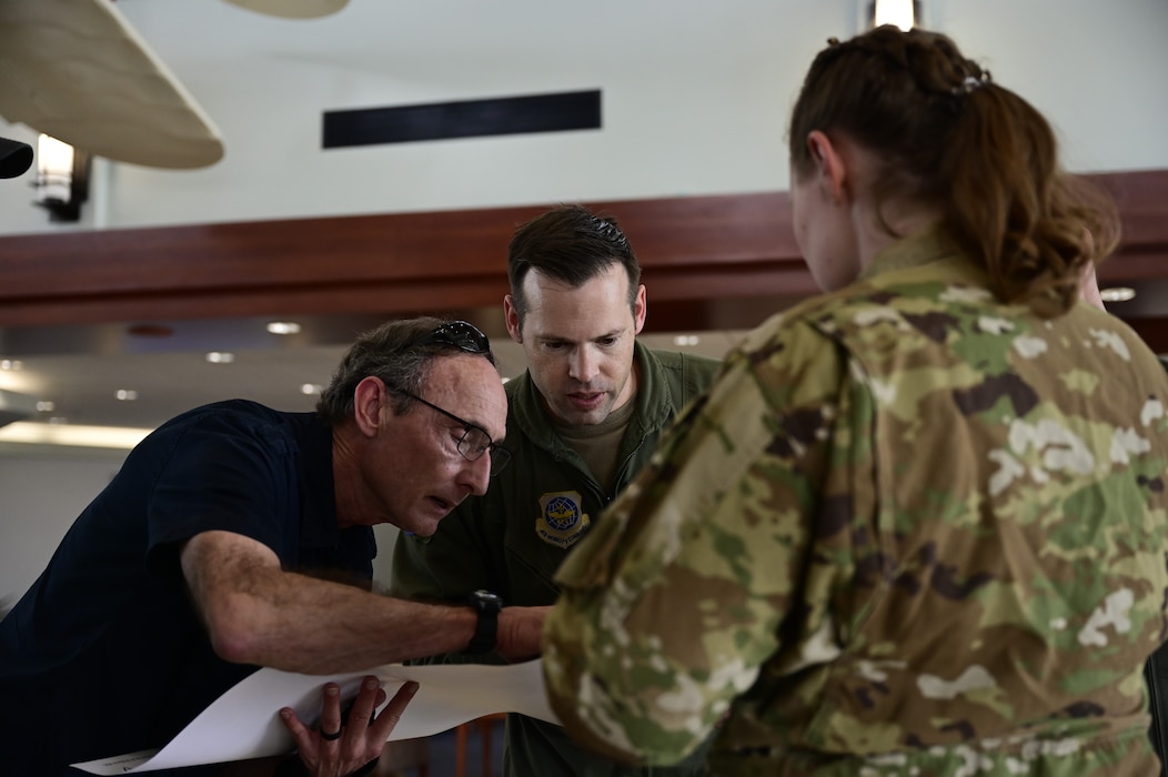 Three people look at a piece of paper.