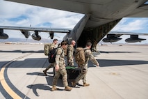 Airmen carry a box to an airplane.
