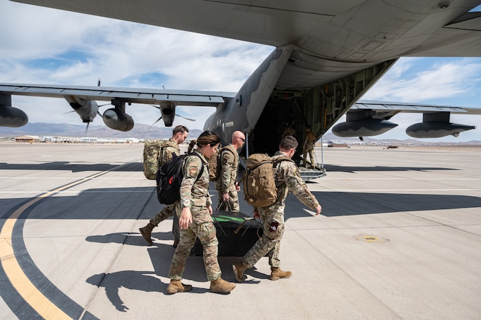 Airmen carry a box to an airplane.