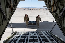 Airmen walk carrying black box to aircraft.
