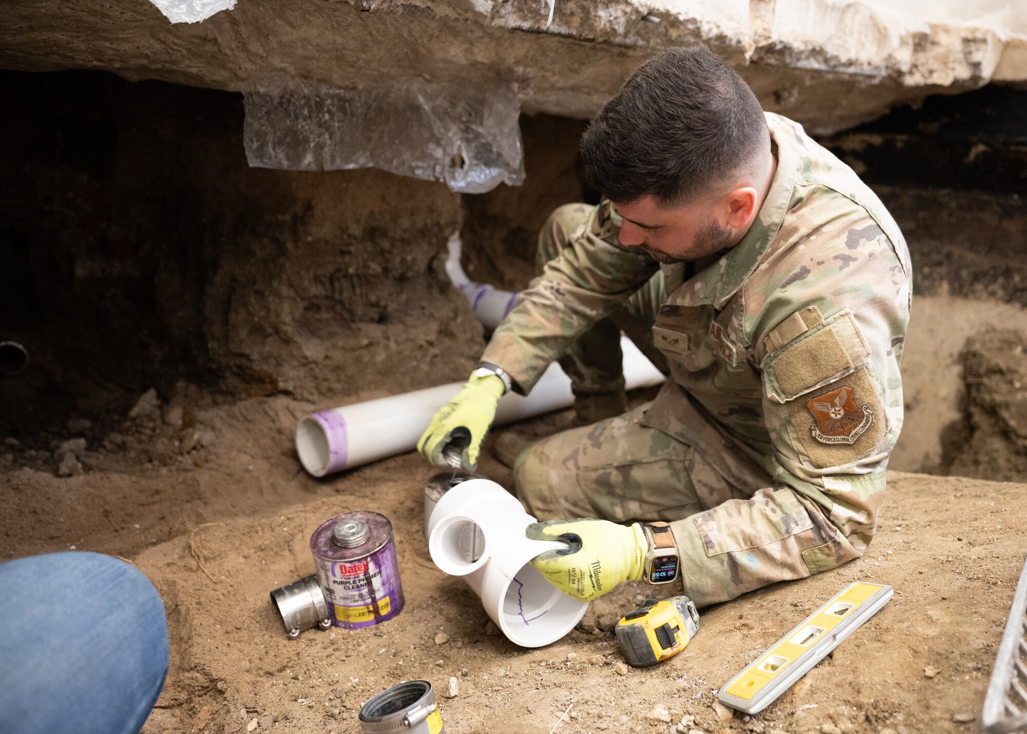 An Airman prepares PVC pipes inside a hand-excavated command suite.