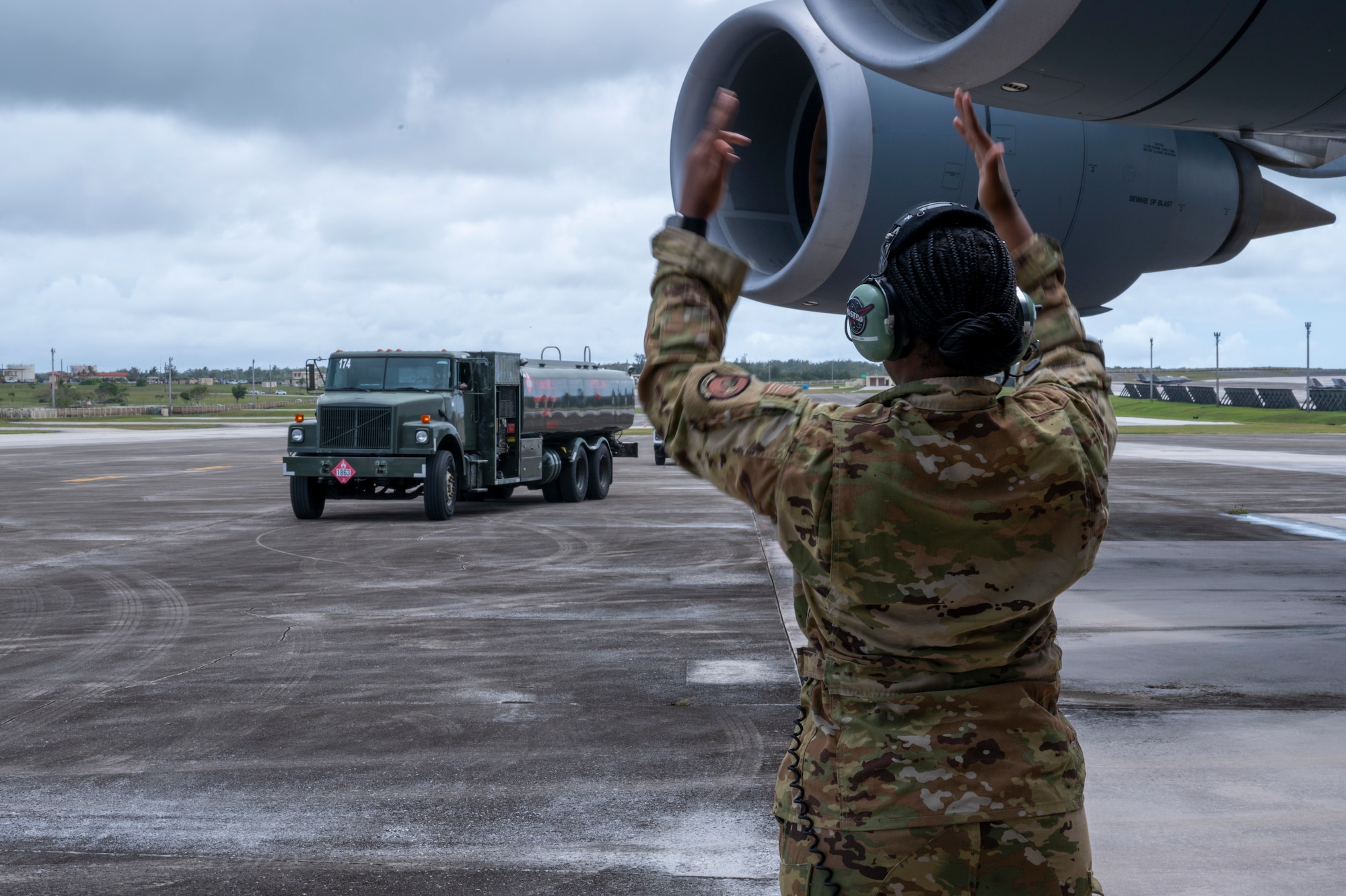 An Airman from the 9th Airlift Squadron guides an R-11 Refueler to a C-5M Super Galaxy at Andersen Air Force Base, Guam, April 29, 2025. The Airmen used the refueler to practice wet-wing defueling techniques during Project Carabao. (U.S. Air Force photo by Airman Xavier Romero)