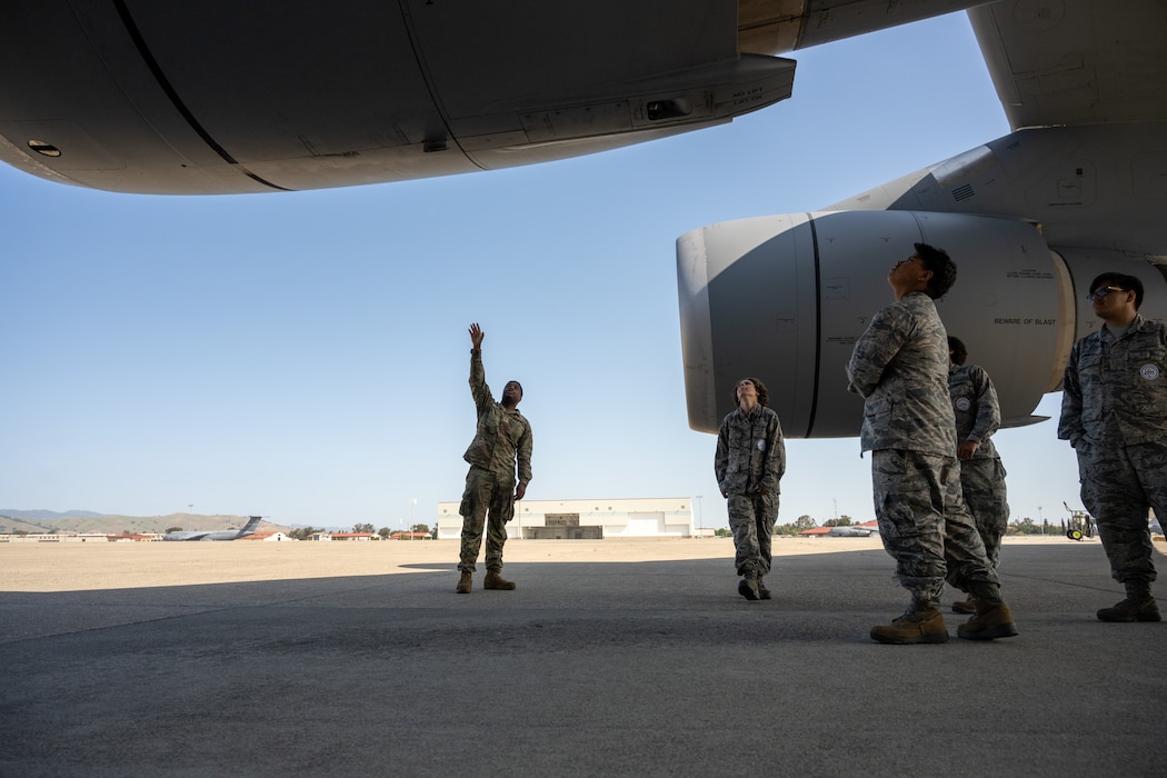 An Airman shows JROTC cadets the engine of a C5