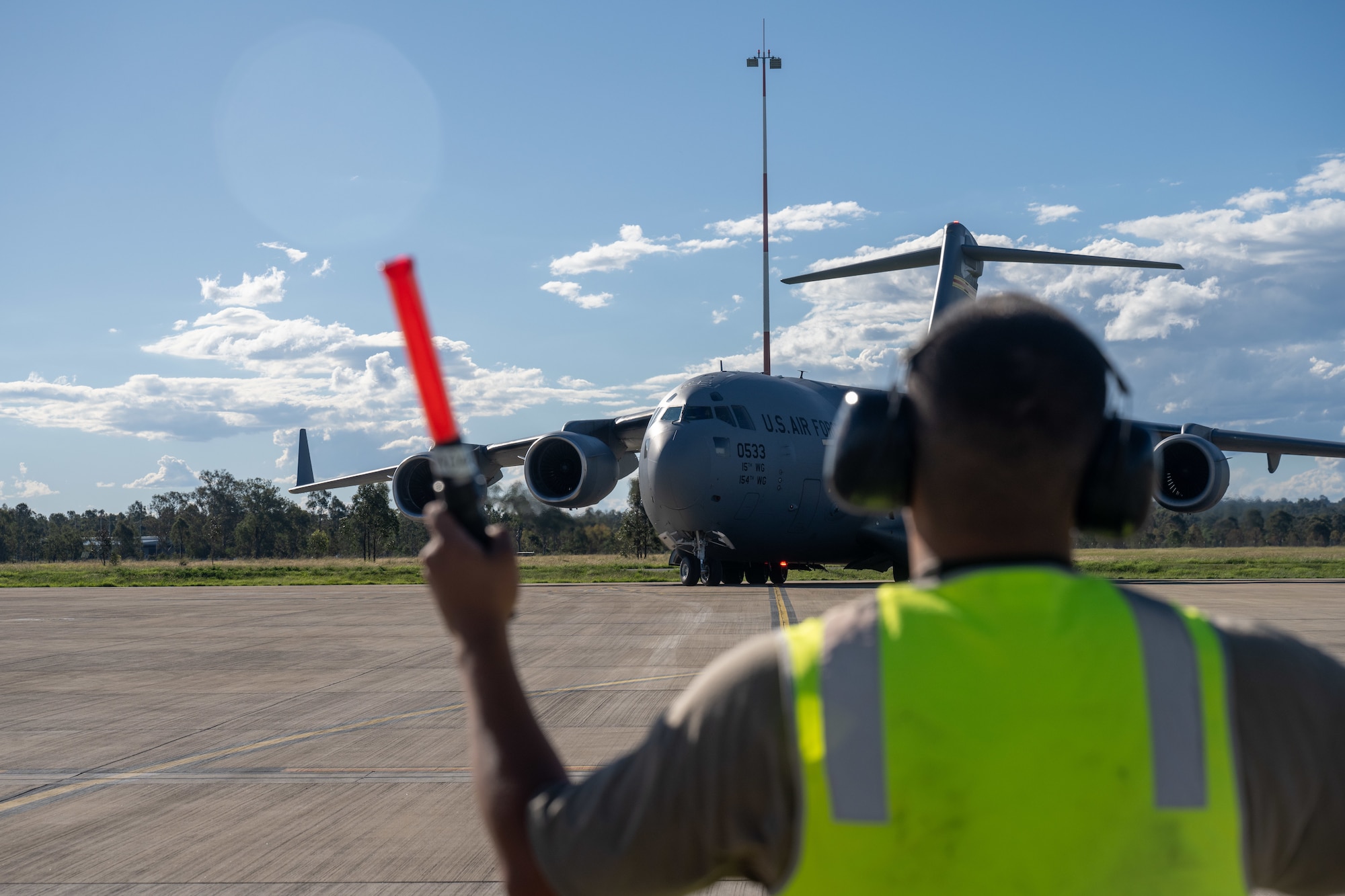 A U.S. Air Force Airmen guides a C-17 to its parking spot in Brisbane, Queensland, Australia.
