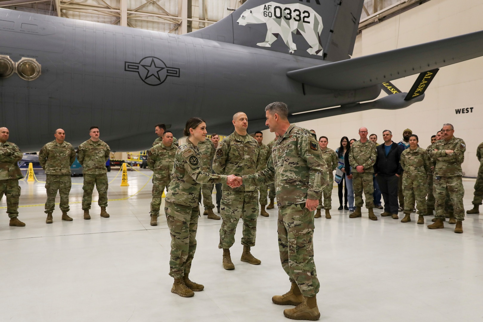 General Nordhaus shakes hands with an Airman in front of a large, cargo plane.