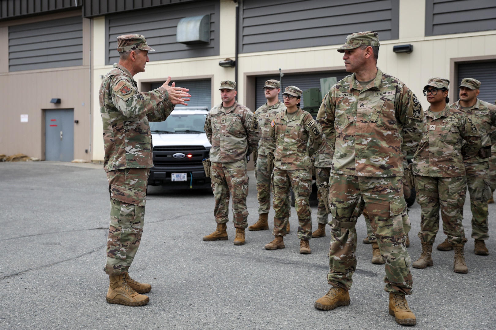 General Nordhaus stands on the left speaking to a group of soldiers standing in formation, looking at him.
