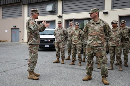 General Nordhaus stands on the left speaking to a group of soldiers standing in formation, looking at him.