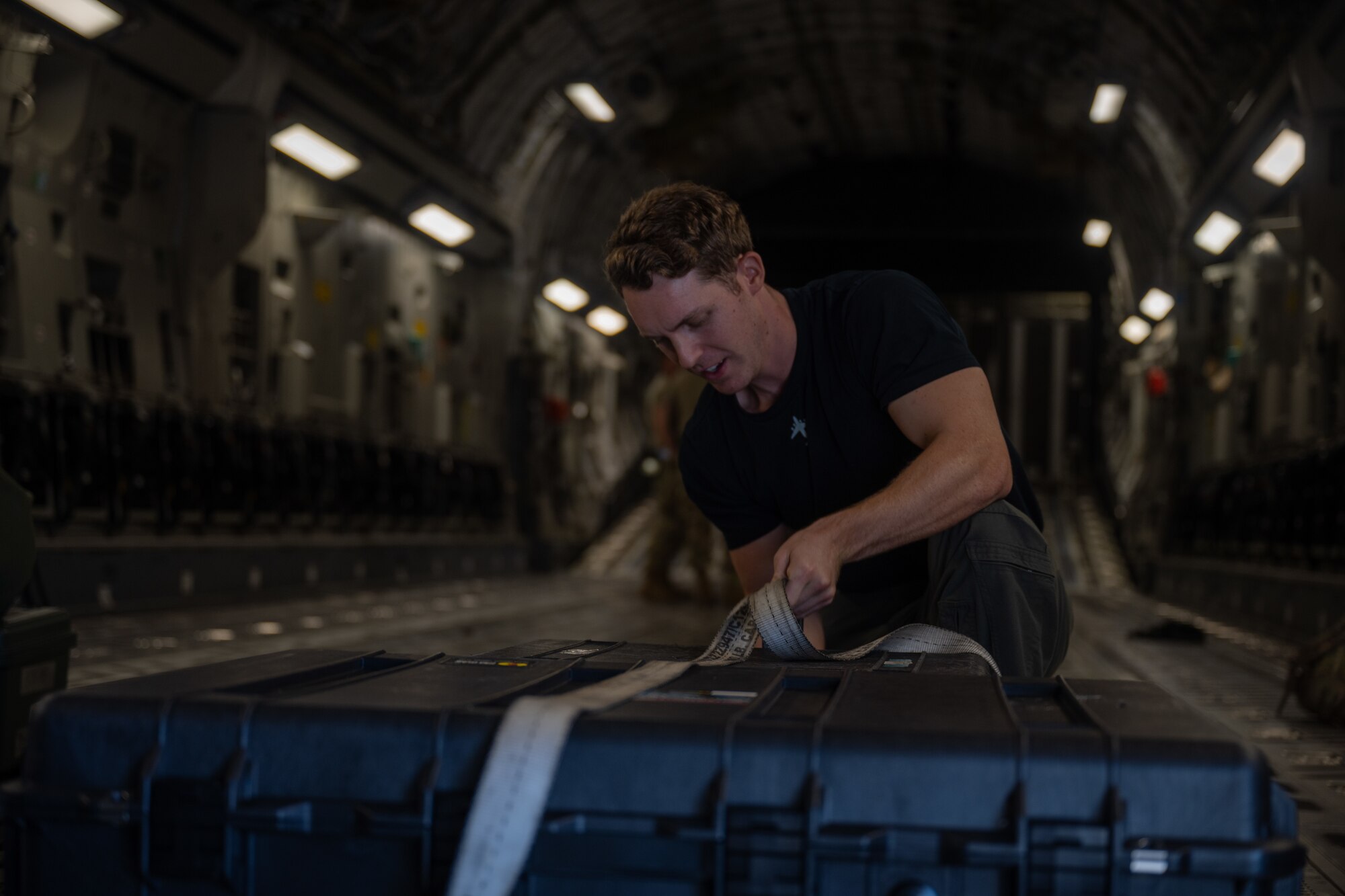 A Royal Australian Air Force aircrew member secures equipment inside of a C-17 Globemaster III.