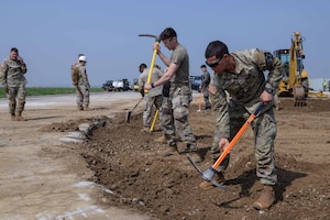 Members of the U.S. Air Force, U.S. Army, Republic of Korea Air Force and ROK Army loosen rock material in a large crater during IRON RADR at Osan Air Base, Republic of Korea, April 24, 2025.  During the exercise, one large and six small craters were restored using legacy and rapid airfield damage repair techniques. IRON RADR is the first complex, joint and combined exercise on Osan AB that tests, evaluates and prepares civil engineers to safely conduct RADR operations in a simulated contingency environment. (U.S. Air Force photo by Staff Sgt. Kahdija Slaughter)