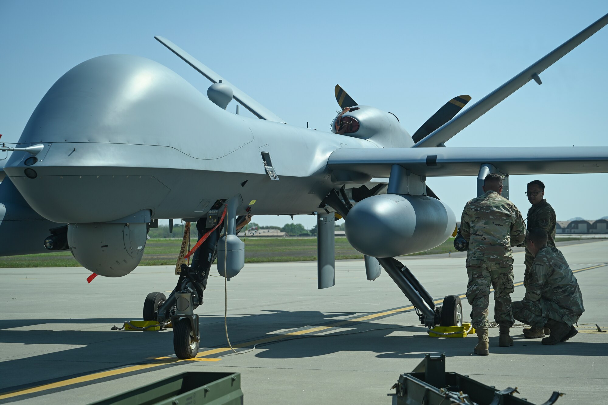 Senior Airman Eduardo Ledezma, Tech. Sgt. Kristopher Speir, and Tech Sgt. Aldrich Aldana, 163d Attack Wing MQ-9 Reaper armament systems specialists, load an AGM-114 Hellfire missile onto an MQ-9 Reaper at Kunsan Air Base.
