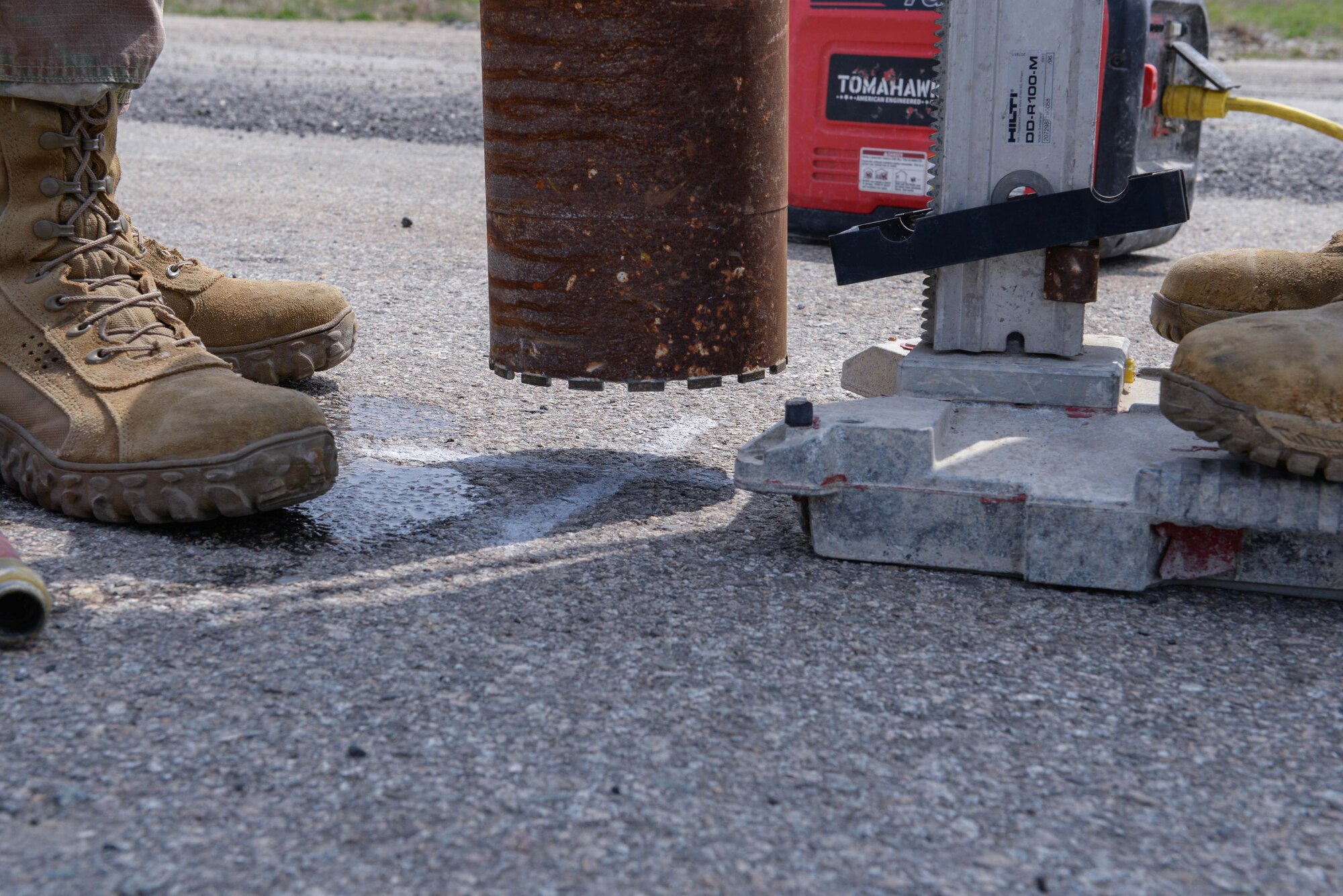U.S. Air Force Staff Sgt. John McCardy, 51st Civil Engineer Squadron heavy equipment supervisor, left, and Senior Airman Jose McRae, 51st CES heavy equipment journeyman, prepare to drill a hole into an asphalt airfield pad at Osan Air Base, Republic of Korea, April 16, 2025. A total of six holes were drilled into asphalt and concrete airfield pads, making room for the 51st CES explosive ordnance Airmen to create small craters with ground upheaval. These preparatory operations laid the realistic foundation for the first complex, joint and combined IRON RADR exercise to test, evaluate, and prepare engineers to safely conduct rapid airfield damage repair operations in a simulated contingency environment. (U.S. Air Force photo by Staff Sgt. Kahdija Slaughter)