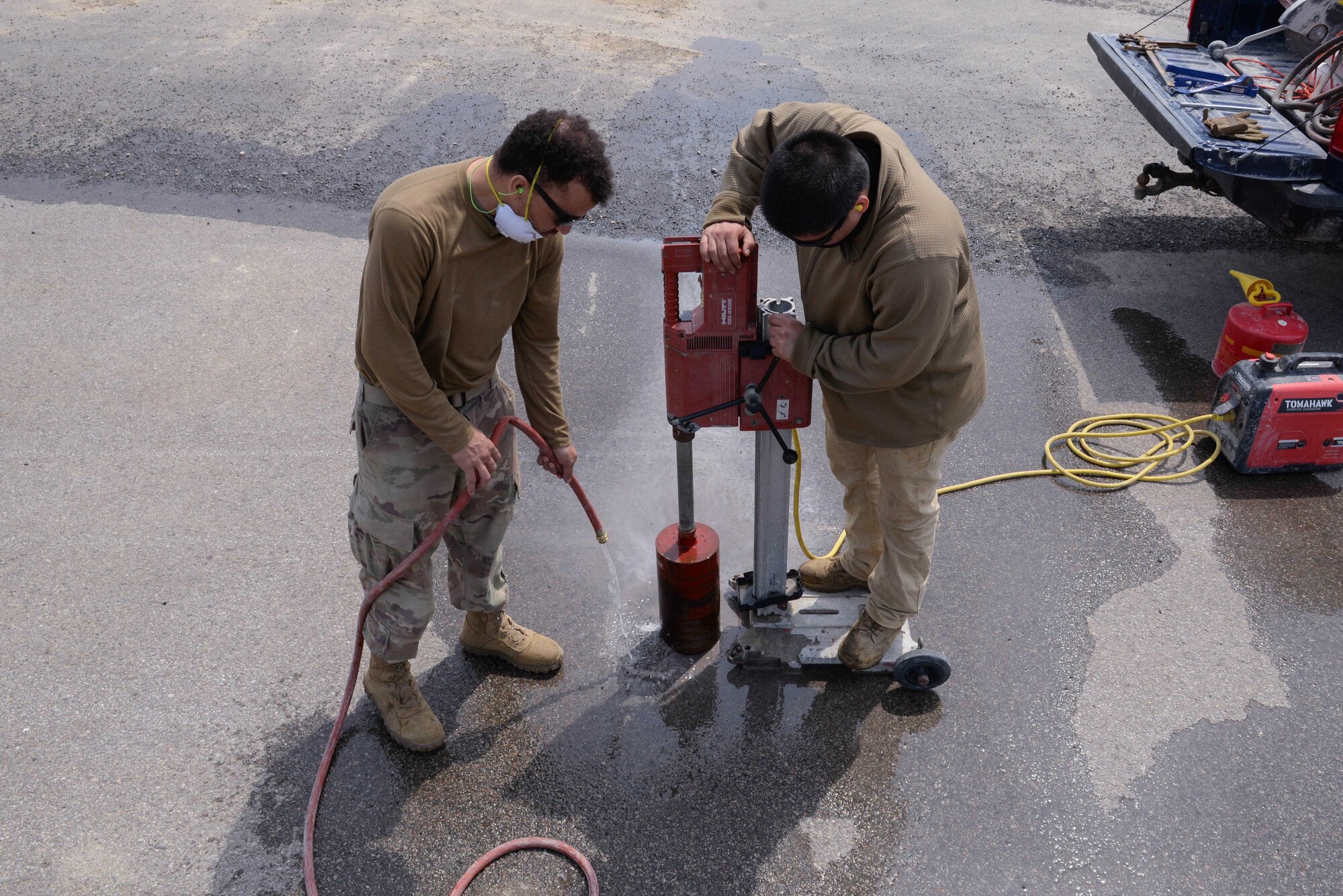 U.S. Air Force Staff Sgt. John McCardy, 51st Civil Engineer Squadron heavy equipment supervisor, left, and Senior Airman Jose McRae, 51st CES heavy equipment journeyman, drill a hole into an asphalt airfield pad at Osan Air Base, Republic of Korea, April 16, 2025. After six holes were drilled, Airmen from the explosive ordnance disposal flight packed the holes with dynamite, TNT and C4 explosives, ultimately blasting small craters that mimic damage from ballistic and airfield penetrator missiles. The craters were restored during the first complex, joint and combined IRON RADR exercise to test, evaluate and prepare civil engineers to safely conduct rapid airfield damage repair operations in a simulated contingency environment. (U.S. Air Force photo by Staff Sgt. Kahdija Slaughter)