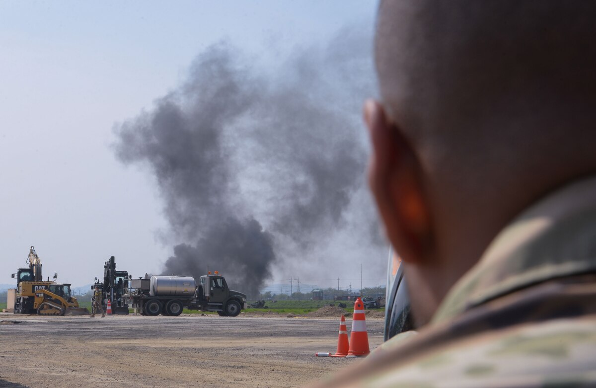 U.S. Soldiers assigned to the 11th Engineering Battalion pause rapid airfield damage repair operations to take cover behind heavy equipment during IRON RADR at Osan Air Base, Republic of Korea, April 24, 2025. The goal of IRON RADR was to test, evaluate and prepare joint and allied engineers to respond to simulated threats during repair operations; increasing survivability from continued air and ground attacks. (U.S. Air Force photo by Staff Sgt. Kahdija Slaughter)