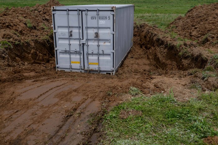 Members of the 51st Civil Engineer Squadron place a cargo container in a berm ditch during IRON RADR at Osan Air Base, Republic of Korea, April 24, 2025. The IRON RADR exercise included preparing and burying expedient shelters while teams of U.S. Air Force, U.S. Army, ROK Air Force and ROK Army engineers completed rapid airfield damage repair operations and simultaneously responded to several simulated attack scenarios. (U.S. Air Force photo by Staff Sgt. Kahdija Slaughter)