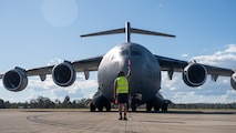 A U.S. Air Force Airmen guides a C-17 to its designated parking spot in Brisbane, Queensland, Australia.