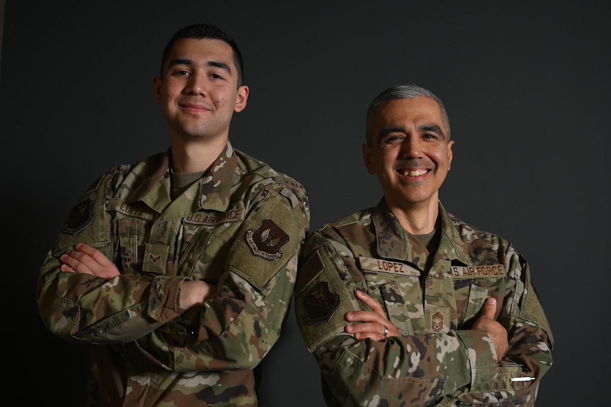 Father and son stand together and pose for a photo as service members.