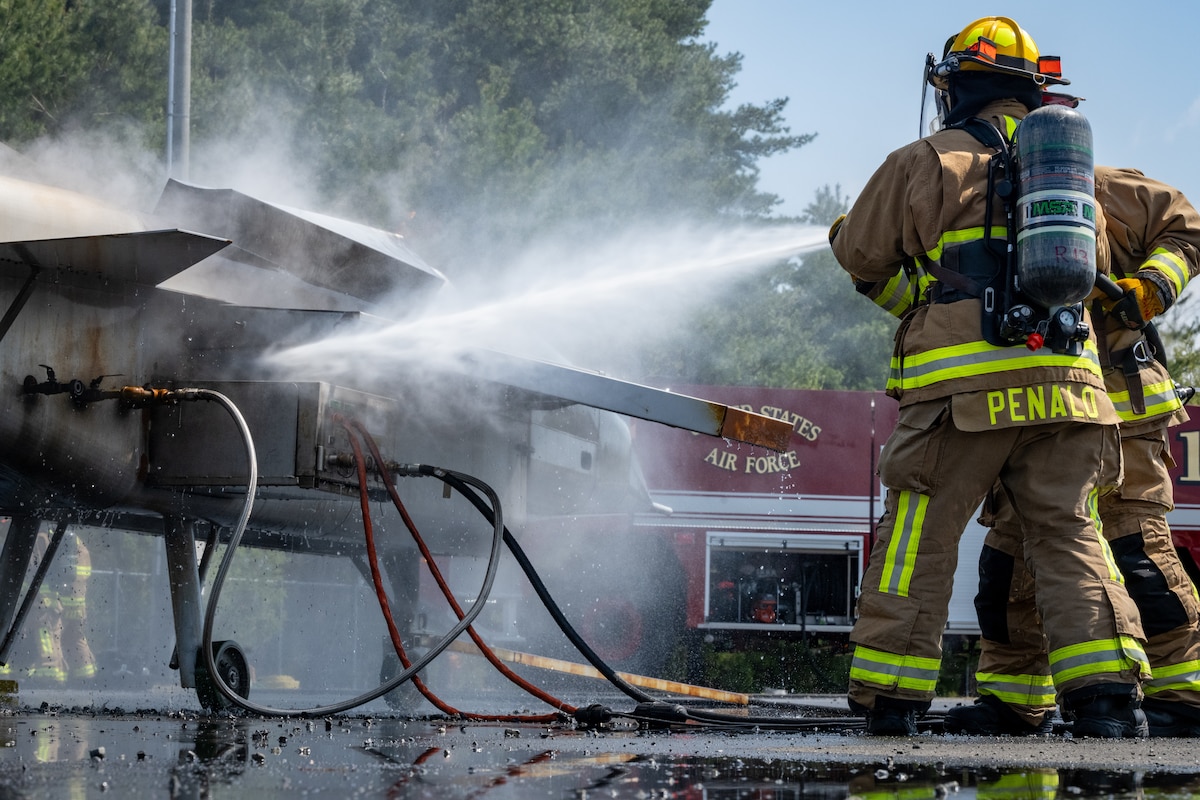 U.S. Air Force Airman Acosta Penalo, left, and Keisuke Kawamura, 35th Civil Engineer Squadron Fire Department firefighters, spray a burning simulated aircraft during a controlled burn exercise at Misawa Air Base, Japan, April 21, 2025. Engaging directly with live-fire scenarios enhances the 35th Fighter Wing’s operational resilience by refining their emergency response capabilities, ensuring rapid containment of fire threats to protect mission-critical assets and personnel. (U.S. Air Force photo by Airman Hannah Bench)