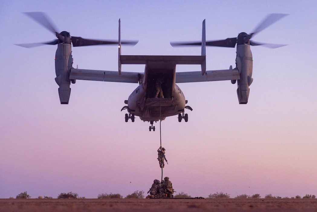 Airmen fasting roping from a MV-22