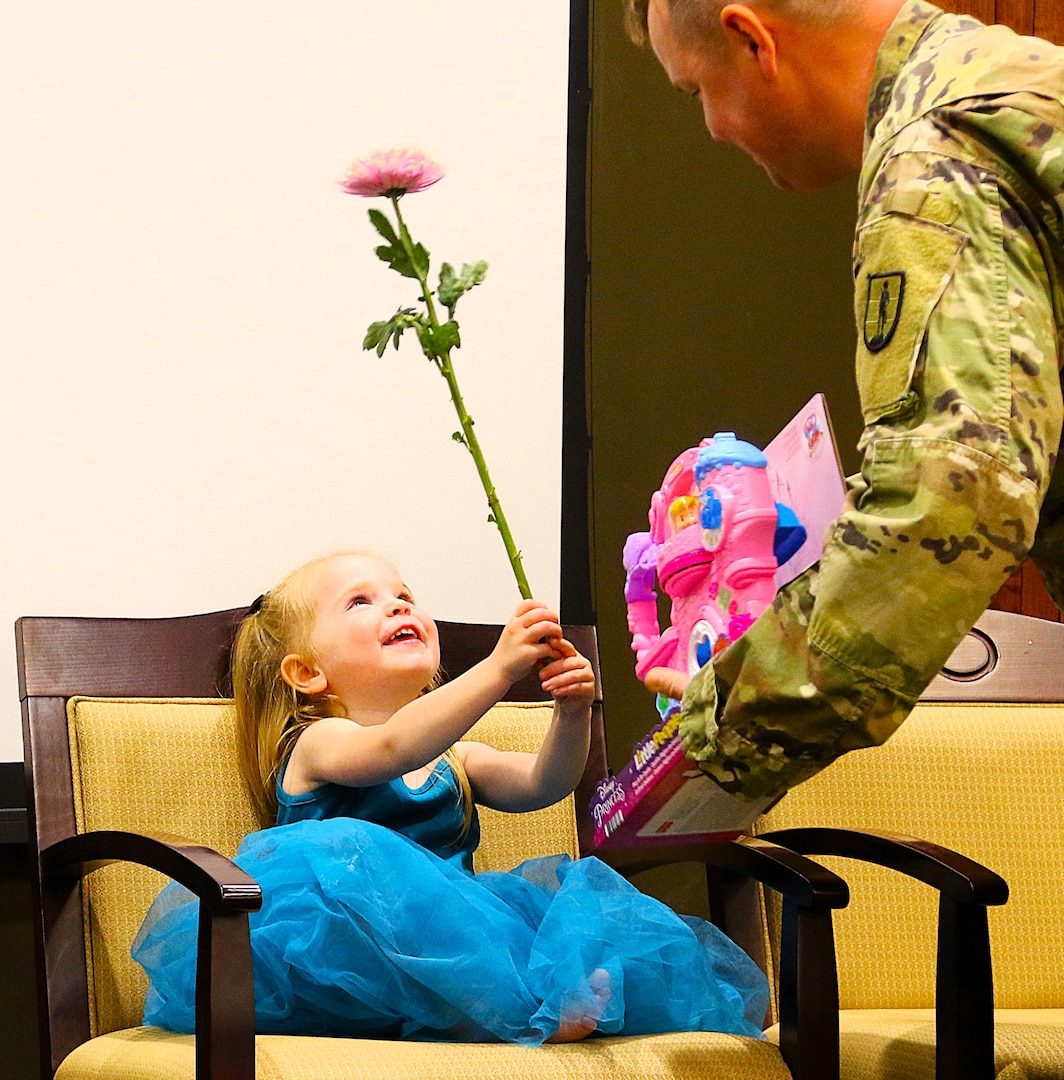 Sgt. 1st Class Sean Fortune gives his 2-year-old daughter, Savannah, a Disney Little Princess toy while she shows him a flower during his retirement ceremony.