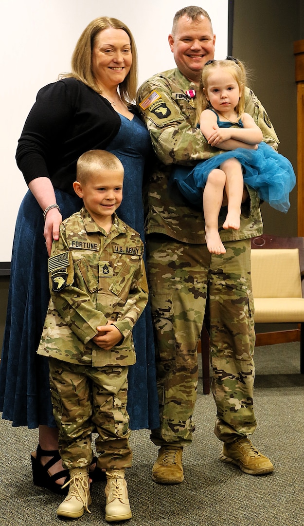Sgt. 1st Class Sean Fortune holds his 2-year-old daughter, Savannah, while his spouse, Stefanie, and 6-year-old son, Maverick, pose for a family photo after his retirement ceremony.