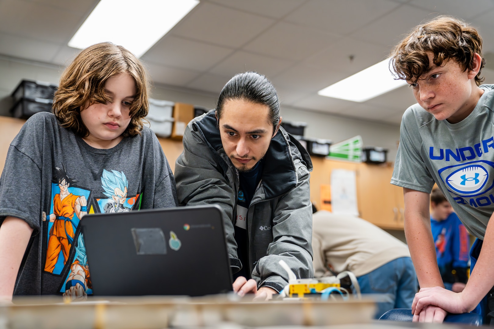 True Soria, a computer scientist at the Naval Surface Warfare Center Dahlgren Division (NSWCDD), mentors students at King George Middle School during the Robotics Week. This program is part of NSWCDD's in-classroom NSWCDD K-12 STEM Outreach Program initiatives, which aim to inspire local youth to become the next generation of scientists and engineers. (Dorina Watermolen/NSWCDD photo)