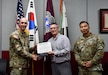 Wally Edwards, center, safety and occupational health manager for U.S. Army Medical Logistics Command, presents the safety excellence streamer award to the U.S. Army Medical Materiel Center-Korea on April 22 at Camp Carroll, Republic of Korea. Receiving the award are USAMMC-K Commander Lt. Col. Nathan Wagner, left, and Master Sgt. Jojo Ada, senior enlisted adviser.