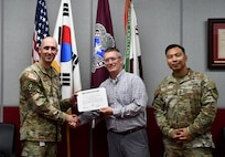 Wally Edwards, center, safety and occupational health manager for U.S. Army Medical Logistics Command, presents the safety excellence streamer award to the U.S. Army Medical Materiel Center-Korea on April 22 at Camp Carroll, Republic of Korea. Receiving the award are USAMMC-K Commander Lt. Col. Nathan Wagner, left, and Master Sgt. Jojo Ada, senior enlisted adviser.