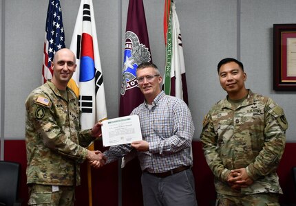 Wally Edwards, center, safety and occupational health manager for U.S. Army Medical Logistics Command, presents the safety excellence streamer award to the U.S. Army Medical Materiel Center-Korea on April 22 at Camp Carroll, Republic of Korea. Receiving the award are USAMMC-K Commander Lt. Col. Nathan Wagner, left, and Master Sgt. Jojo Ada, senior enlisted adviser.
