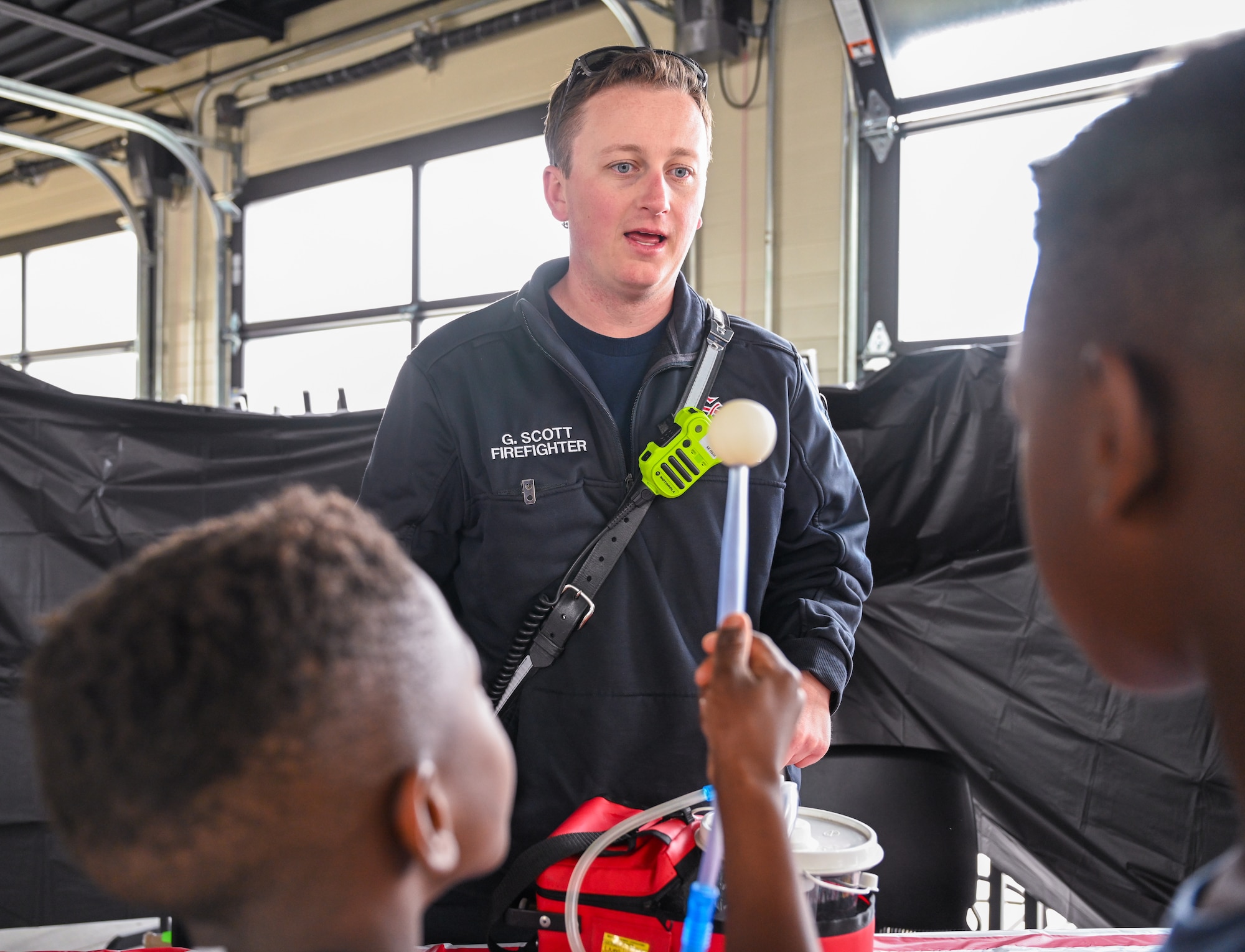 Firefighter provides a demonstration of firefighting equipment to children.