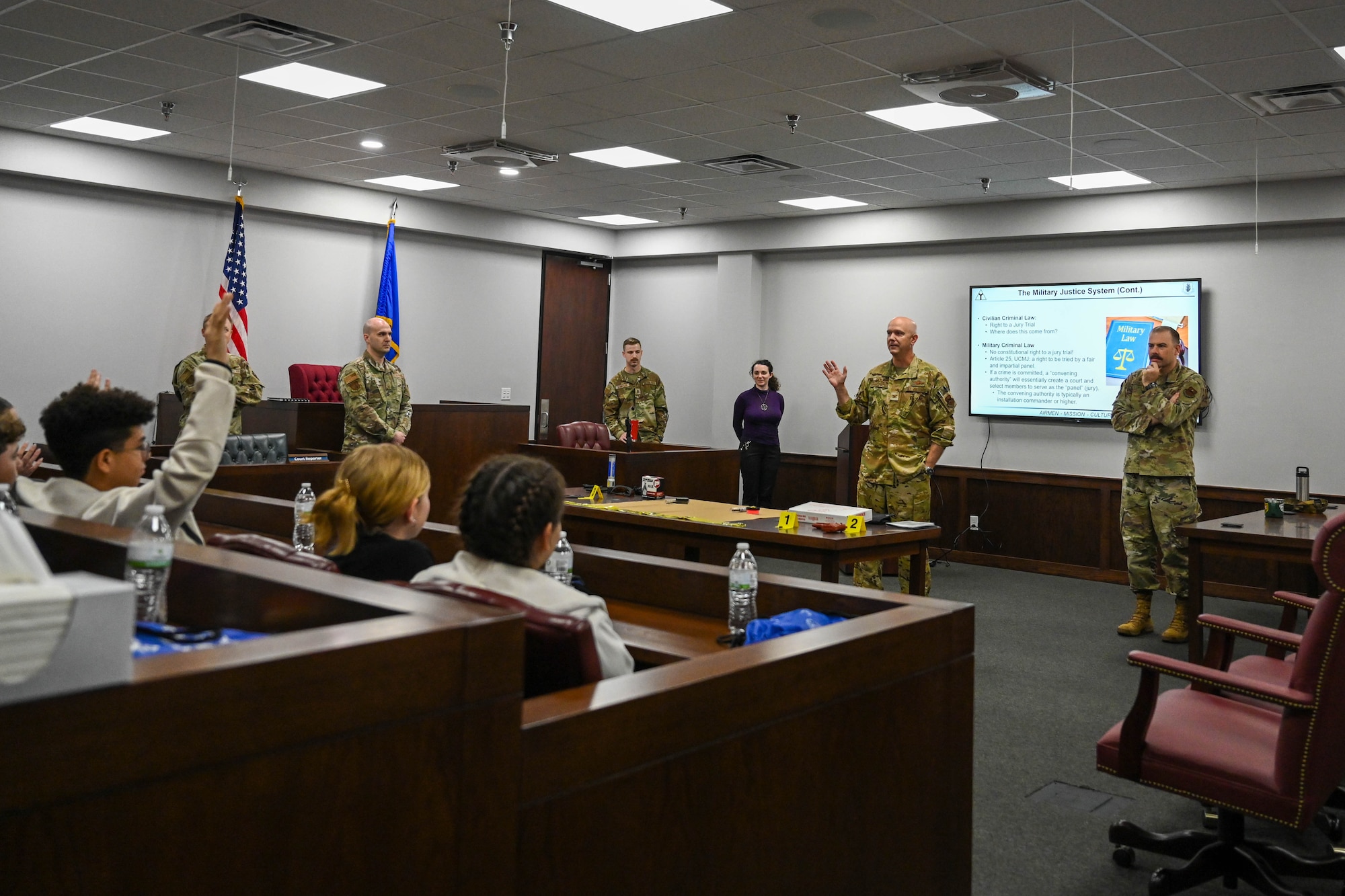 U.S. Air Force Col. Jeff Marshall, 97th Air Mobility Wing (AMW) commander, and Chief Master Sgt. Justin Brundage, 97th AMW command chief, answer questions from Altus Junior High School students during Law Day at Altus Air Force Base, Oklahoma, May 1, 2025. Marshall and Brundage welcomed the students as they arrived for the mock trial. (U.S. Air Force photo by Airman 1st Class Lauren Torres)