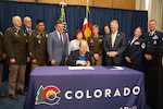 The Adjutant General of Colorado U.S. Army Maj. Gen. Laura Clellan and other members of the Colorado National Guard watch as Governor Jared Polis signs into law SB25-247, Tuition Waiver for Colorado National Guard members, at the Colorado State Capitol, Denver, May 1, 2025. (U.S. Army National Guard photo by Sgt. 1st Class Joseph K. VonNida)