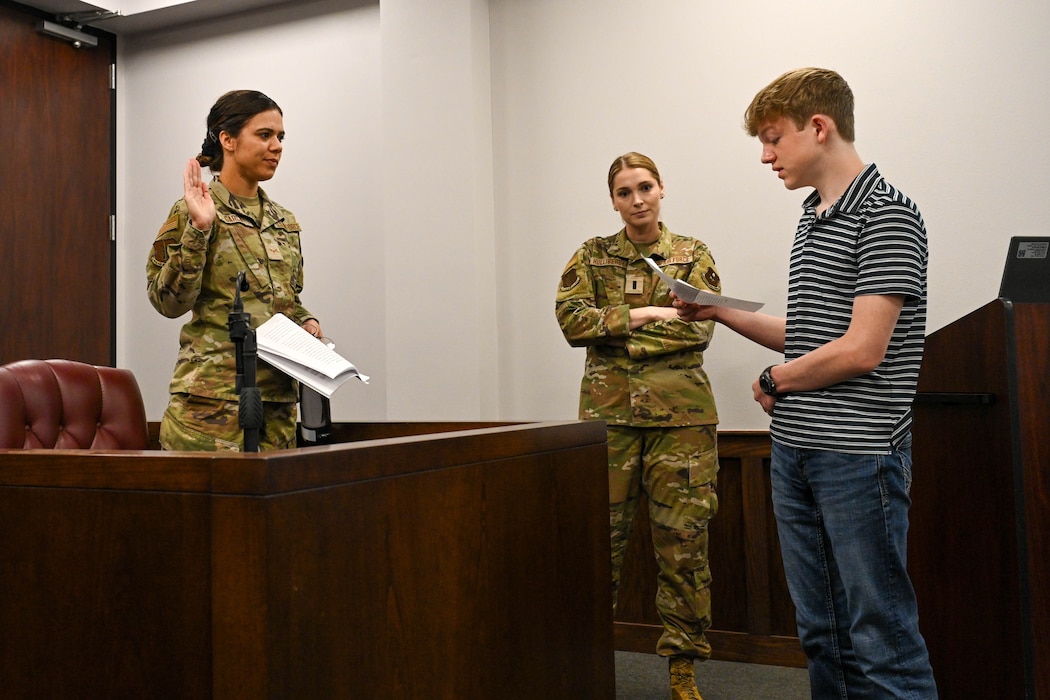 U.S. Air Force Airman 1st Class Shiaslynn Garcia, 97th Air Mobility Wing Judge Advocate (JA) military justice paralegal, is sworn-in by Ronan, Altus Junior High School student, during a mock trial during Law Day at Altus Air Force Base, Oklahoma, May 1, 2025. Students took turns acting as attorneys and trial lawyers while receiving advice on what to do from JA team members. (U.S. Air Force photo Senior Airman Kari Degraffenreed)