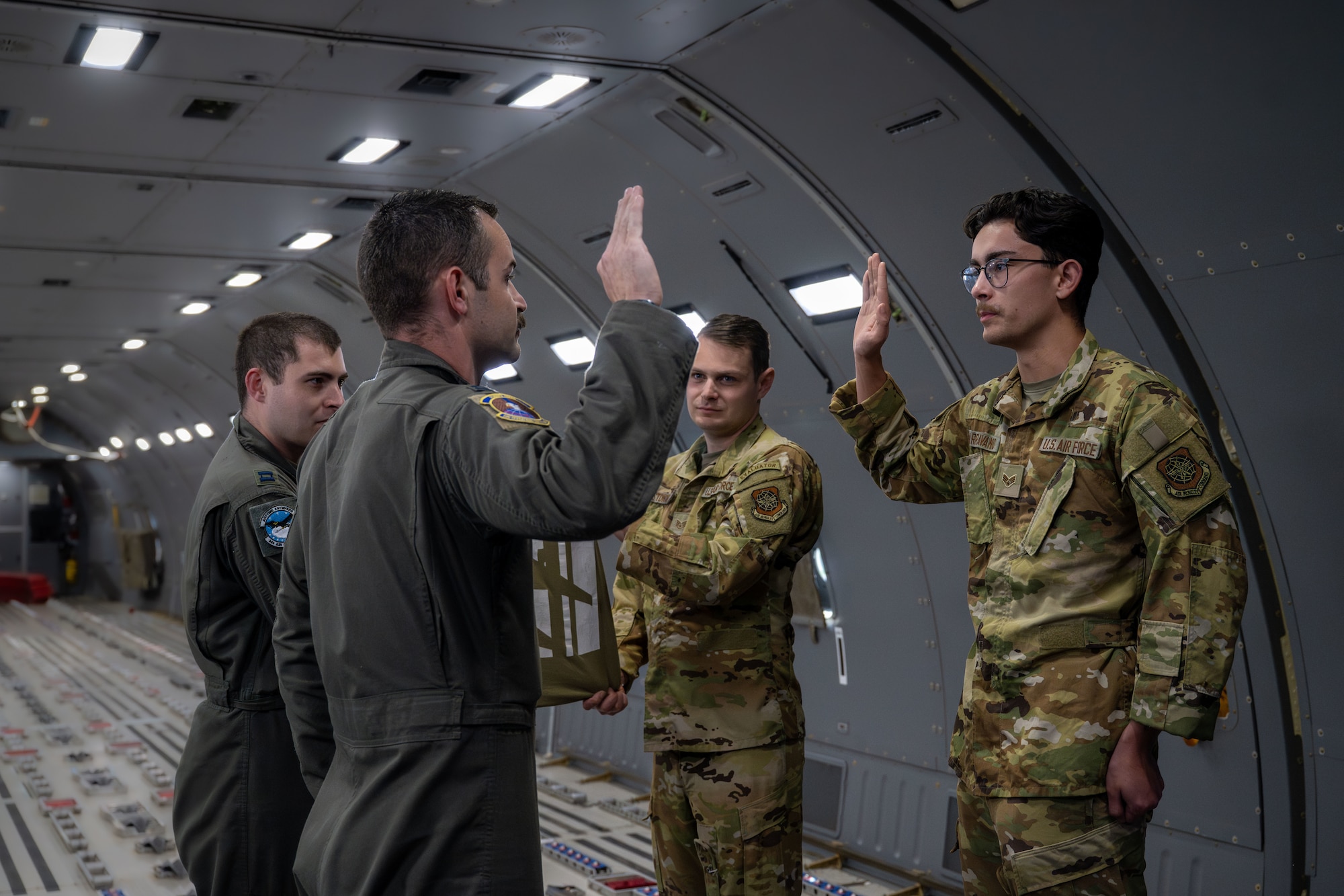 Capt. Cody Nelson, 22nd Operations Support Squadron KC-46A Pegasus pilot, administers the Oath of Enlistment to Senior Airman Kaden Parravano, 22nd Aircraft Maintenance Squadron flying crew chief, in a KC-46 over the Midwestern United States.