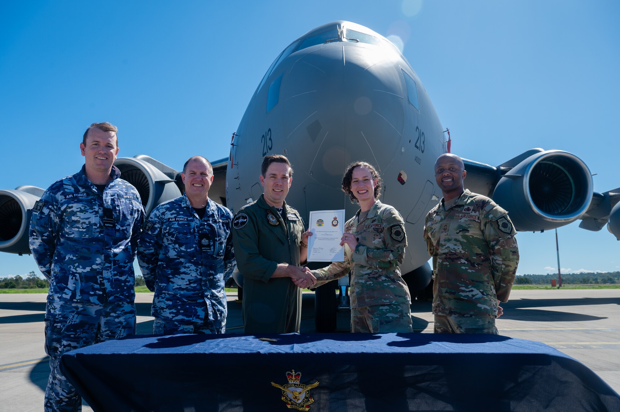 Royal Australian Air Force Commanding Officer Robert Krupinski, 36 Squadron wing commanding officer ,and U.S. Air Force Lt. Col. Deanna McCoy, 15th Aircraft Maintenance Squadron commander, present an agreement document during Global Dexterity 25 on Royal Australian Air Force Base Amberley, Queensland, Australia.