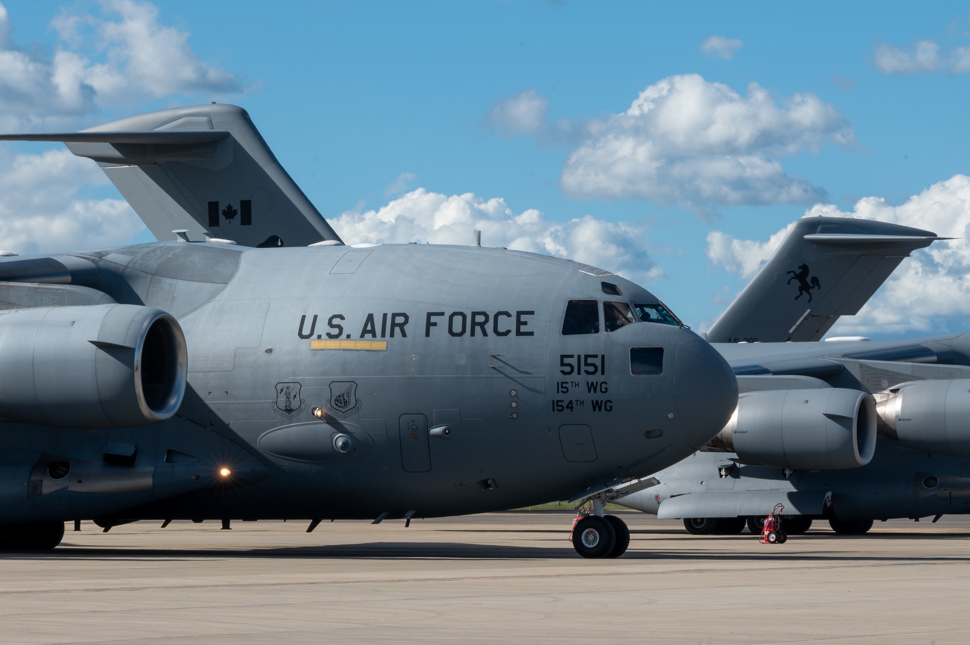 A U.S. Air Force, Royal Canadian Air Force, and Royal Australian Air Force C-17s are lined up next to each other on a flightline.