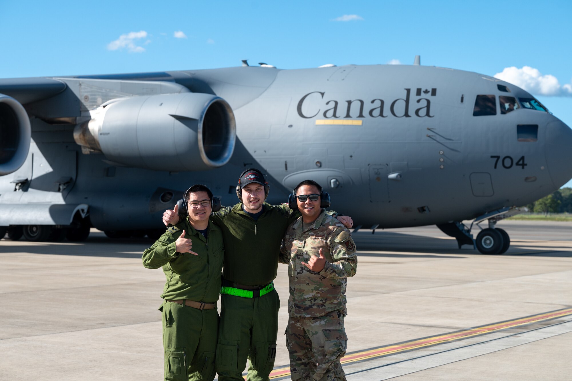 U.S. Air Force member and Royal Canadian Air Force members pose in front of a RCAF C-17.