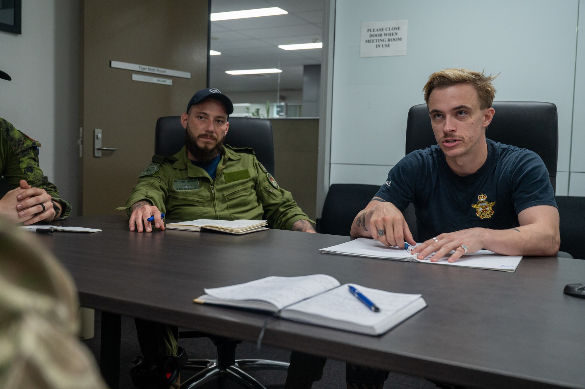 Two servicemembers sit at a conference table discussing future operations