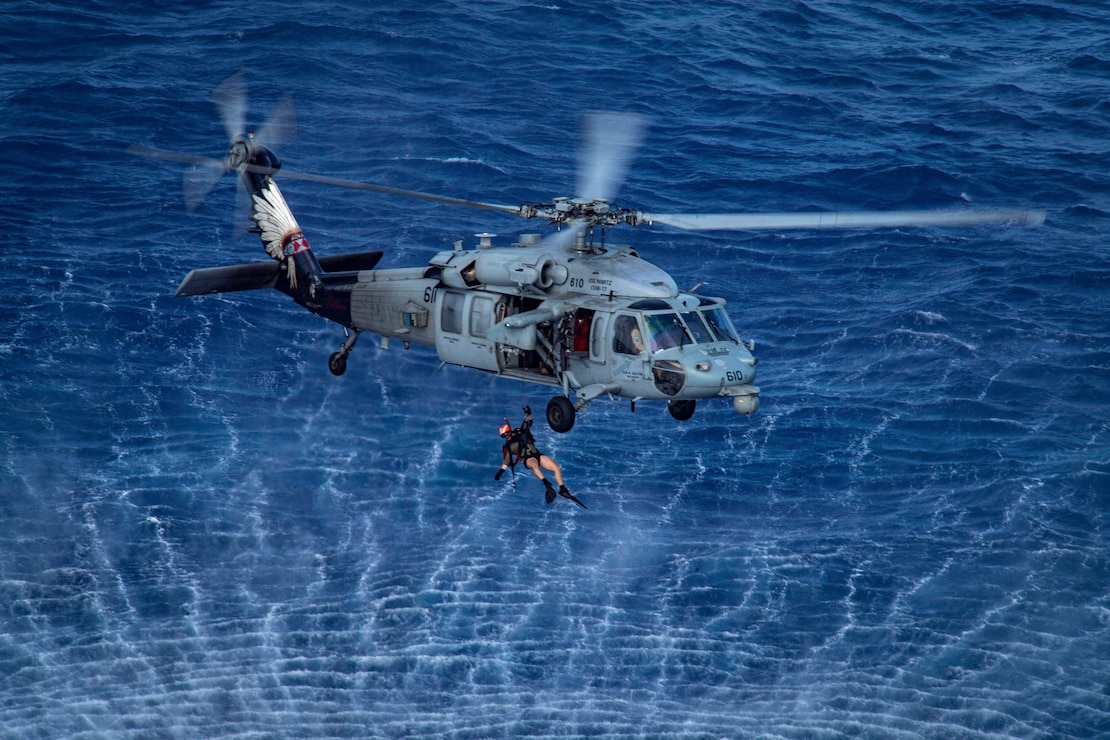A search and rescue swimmer is lifted into an MH-60S Sea Hawk helicopter from the “Indians” of Helicopter Sea Combat Squadron (HSC) 6 during training in the Philippine Sea, April 29, 2025.