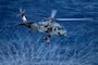 A search and rescue swimmer is lifted into an MH-60S Sea Hawk helicopter from the “Indians” of Helicopter Sea Combat Squadron (HSC) 6 during training in the Philippine Sea, April 29, 2025.