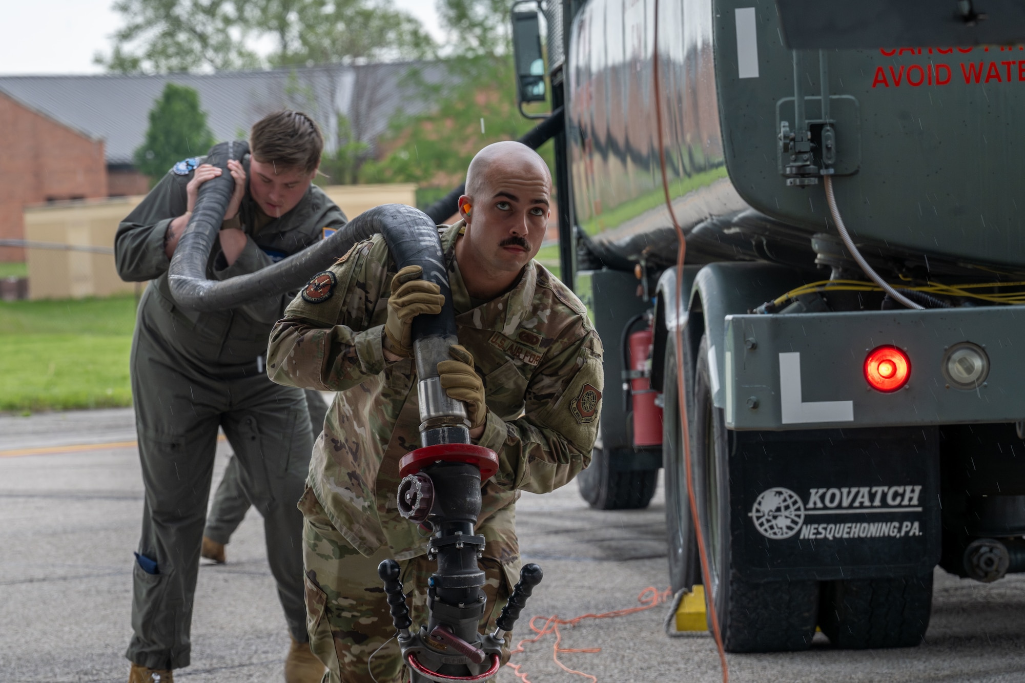 From left, Airman 1st Class Allen Knight, 344th Air Refueling Squadron KC-46A Pegasus boom operator and Airman 1st Class Nathaniel Rambally, 375th Logistics Readiness Squadron fuels distribution operator, carry a fuel hose.