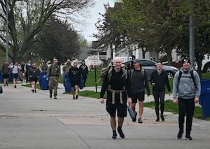 Airmen march through the Coffman Heights neighborhood during a ruck march memorializing Capt. Nathan Nylander, a 25th Operational Weather Squadron weather officer killed in Afghanistan in 2011, on Offutt Air Force Base, Nebraska, April 25, 2025. More than 50 Airmen participated in the event. (U.S. Air Force photo by Daniel Martinez)
