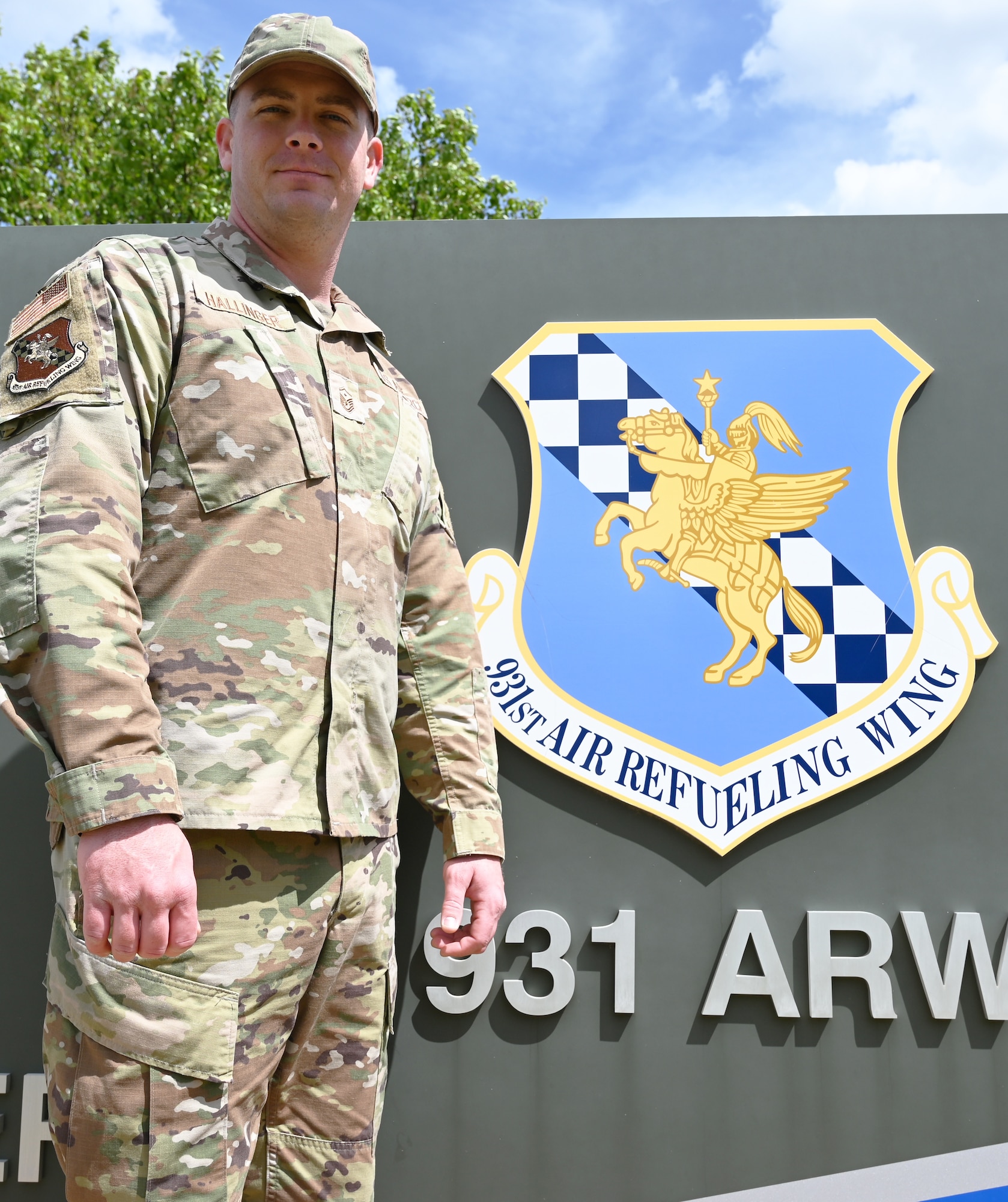 Image of Master Sgt. Travis Hallinger in front of base sign.