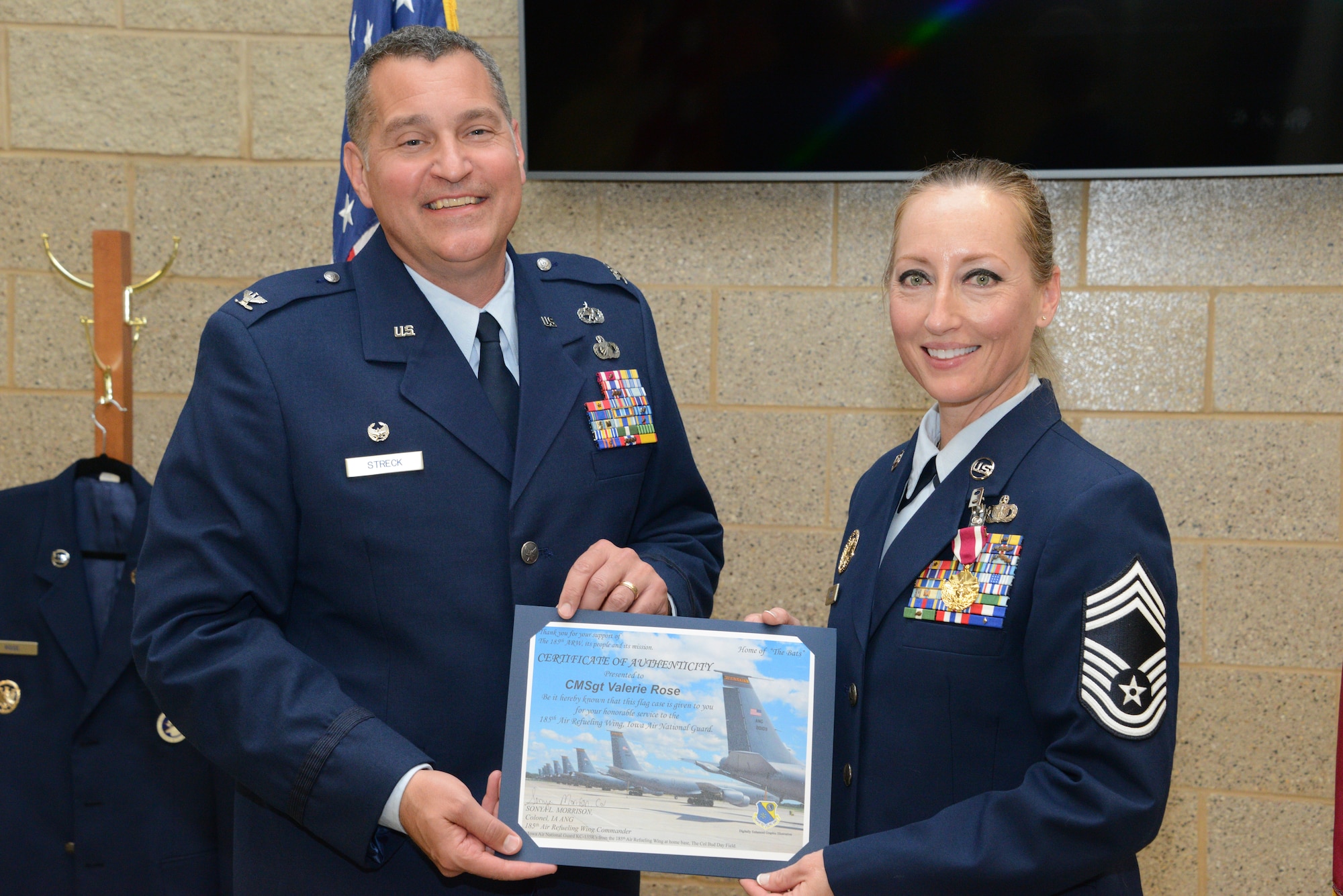 Col. Shawn Streck, 185th Air Refueling Wing Maintenance Group Commander, left, hands a flag certificate of authenticity to Chief Master Sergeant Valerie Rose, outgoing Maintenance Group Chief, right