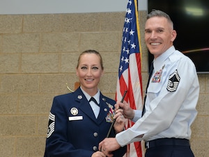 Chief Master Sgt. Valerie Rose, retired 185th Maintenance Group Chief, left, hands a collapsable police baton to her husband, Senior Master Sgt. Bradley Rose, incoming 185th Maintenance Group Chief, right,