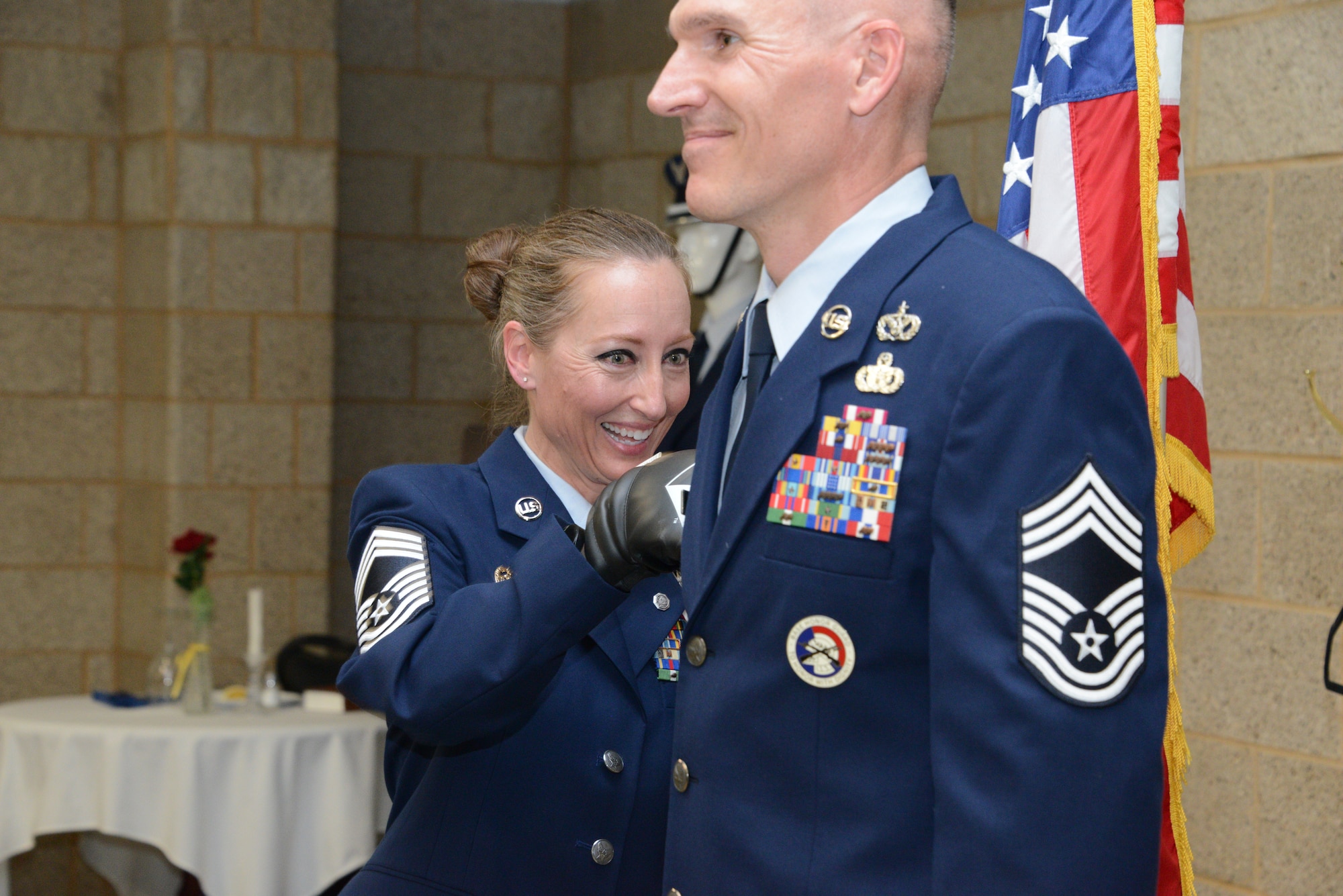 Chief Master Sgt. Valerie Rose, retired 185th Maintenance Group Chief, left, performs the tradition of punching on a new rank for her husband, Chief Master Sgt. Bradley Rose, incoming 185th Maintenance Group Chief, right,