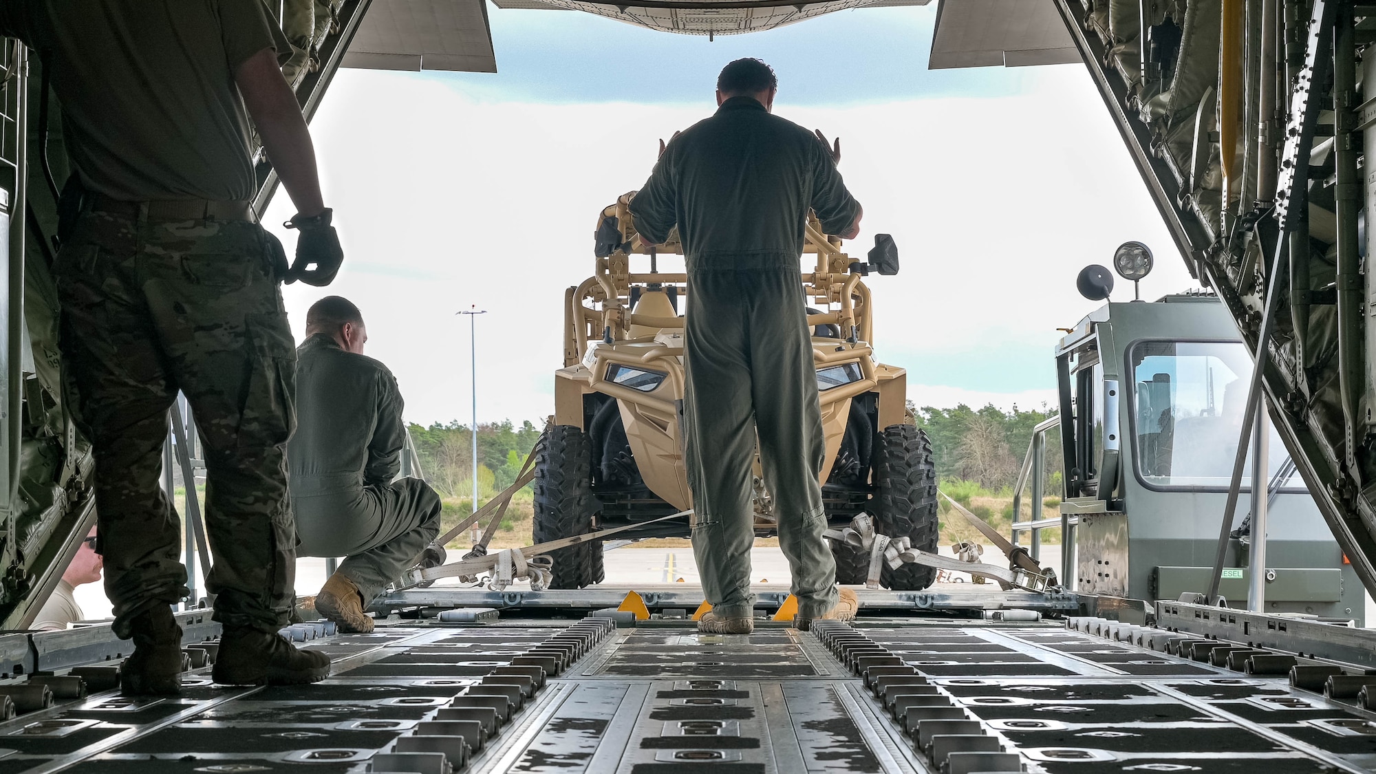 U.S. Airmen load a light tactical all-terrain vehicle onto an aircraft