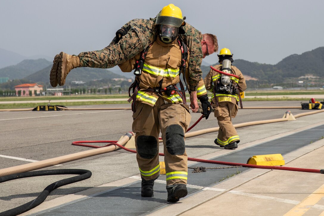 U.S. Marine Corps Cpl. Gabriel Magruder, an aircraft rescue and firefighter, carries Lance Cpl. Landon Stahl, an expeditionary fuels technician, both with Marine Wing Support Squadron 171, Marine Aircraft Group 12, 1st Marine Aircraft Wing, during a simulated emergency at Gwangju Air Base, South Korea, during exercise Freedom Flag 25-1, April 24, 2025. Marines with MWSS-171 conducted medical recovery, removal, and transfer training to sharpen their operational readiness and enhance expeditionary capabilities. FF25-1 is a military exercise between U.S. and Republic of Korea forces designed to enhance readiness through realistic and complex training scenarios. Magruder is a native of Illinois, and Stahl is a native of Indiana. (U.S. Marine Corps photo by Cpl. Chloe Johnson)