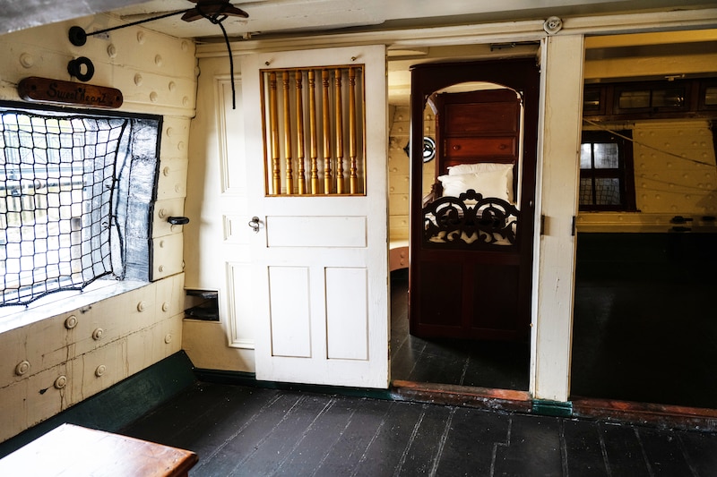 A ship's cabin is shown with a window and doors to other rooms.