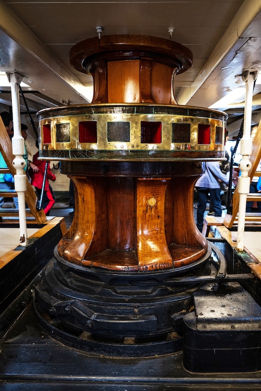 A wooden capstan, which is shaped like big cylinder, sits aboard an old ship.